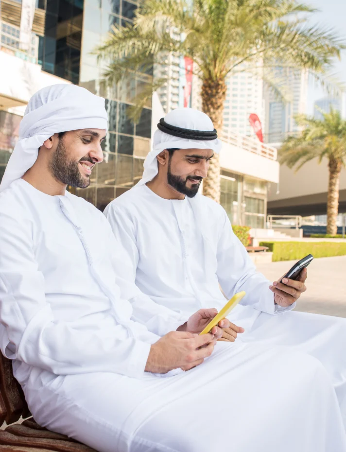 Two men sitting side by side on a wooden bench in a park, engaged in conversation.